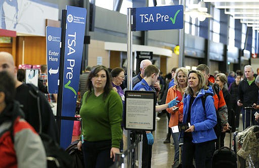 In this March 17, 2016, file photo, travelers authorized to use the Transportation Security Administration's PreCheck expedited security line at Seattle-Tacoma International Airport in Seattle have their documents checked by TSA workers. 