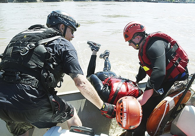 Instructor Mark Cado, left, and Shane Engelhardt pull Anthony Trapani out of the fast-flowing Missouri River on Thursday during training exercises at Summer Fire School.