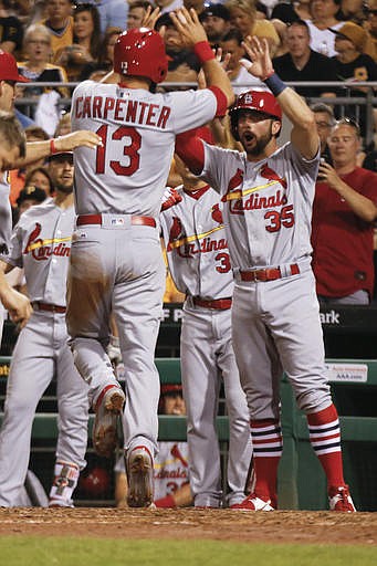 St. Louis Cardinals' Matt Carpenter (13) is greeted by Greg Garcia (35) and other teammates after driving him and Eric Fryer in with a three-run home run during the eighth inning of a baseball game against the Pittsburgh Pirates, Friday, June 10, 2016, in Pittsburgh. 