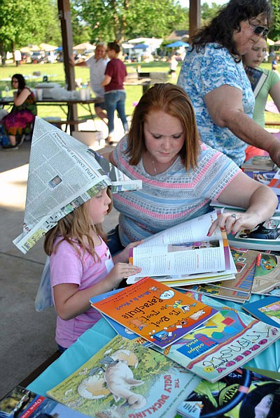 Eldon residents Kayla Scrivner looks at a horse book with her daughter Lilyana during the second annual Reading in the Park Friday at Rock Island Park.  