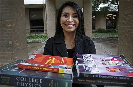In a Thursday, May 19, 2016 photo, Melisa Simon, 17, poses for a photograph with text books for college classes that she took at Eastfield College in Mesquite, Texas. She recently completed her associate degree at Eastfield College through W.W. Samuell Early College High School and will start a "TechTeach" program through Texas Tech in July that will allow her to get a bachelor's degree and teacher certification within one year. 