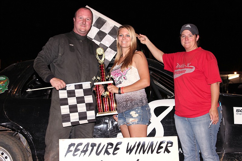 Fred Stotler of St. Charles Police Department accepts the "Battle of the Badges" feature trophy from Double-X Speedway trophy girl, Kelsey Brauner, while DOC Barbara Whittle holds the victory flag, both of California.