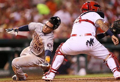 Houston Astros' Carlos Gomez, left, scores past St. Louis Cardinals catcher Yadier Molina on a two-run single by Doug Fister during the seventh inning of a baseball game Tuesday, June 14, 2016, in St. Louis. 