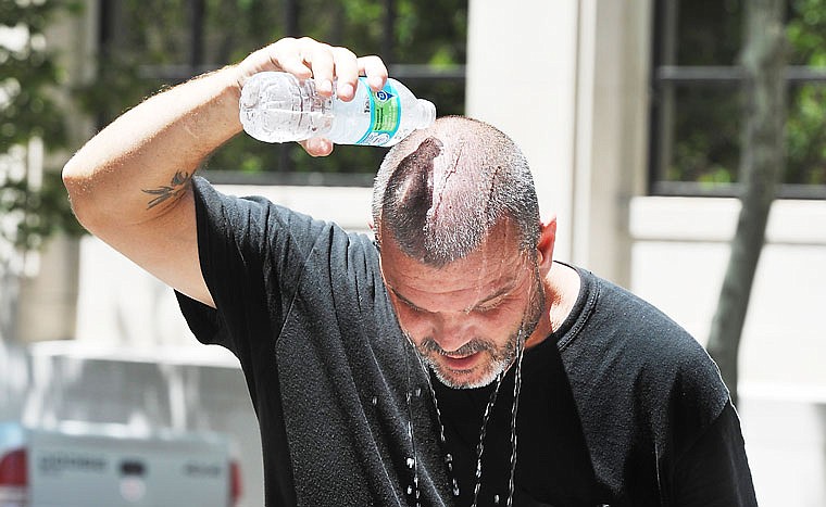 Shawn Laurie, of Wise Production Services, pours cold water over his neck and head to help cool off quickly. Laurie and co-workers were setting up the stage for Thursday Night Live, and the heat from the pavement and nearby buildings made the job a very hot, sweaty one.
