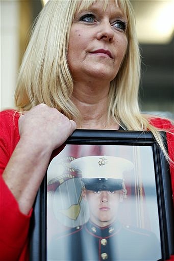 In this photo taken May 17, 2016, Kathy Davis holds a portrait of her son Kindall Johnson for a portrait at Strong Hall on the Missouri State University campus in Springfield, Mo. Johnson, a Marine, MSU student and Delta Sigma Phi member, committed suicide last year. (Guillermo Hernandez Martinez/The Springfield News-Leader via AP)