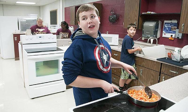 In this Oct. 18, 2015 file photo, Lane Russell, an eighth-grade student at Eldon Middle School, talks to his teacher during an after school Family and Consumer Science class activity. Students in the class created pizza sauce for mini-pizzas to serve to their peers as a part of the school's mission to improve student health.
