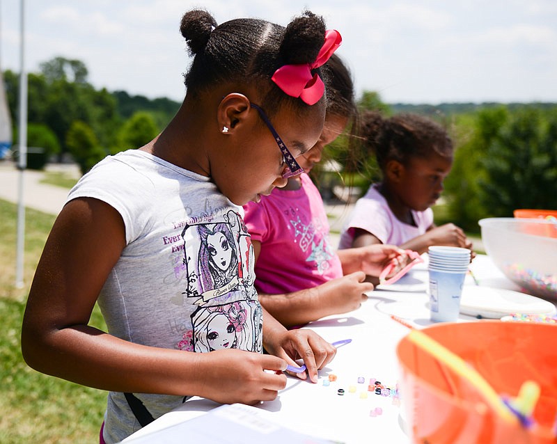 Jeanette McNairy, 5, makes beaded necklaces with other boys and girls at one of the activity stations for children during the Juneteenth celebration at Jefferson City's Ellis-Porter Riverside Park on Saturday.