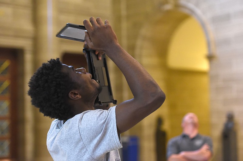 Little Moses, 17, takes pictures on his iPad of the paintings inside the Capitol on Tuesday. Moses is part of a program where students from St. Louis attend State Tech during the summer.