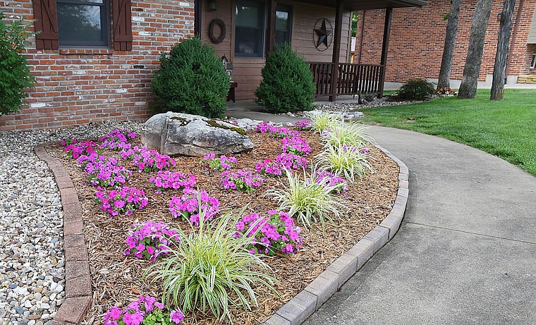 The path to the front door is accented by colorful plants at Rhonda and Darrell Maples' home on Iven Road. The Maples' have brought in a number of rocks to be used as flower bed borders. Also featured in their garden are numerous plants that were handed down from previous generations and locales. 