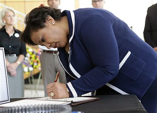 Attorney General Loretta Lynch writes in a book at City Hall expressing sympathy and condolences to the victims of the Pulse nightclub mass shooting, Tuesday, June 21, 2016, in Orlando, Fla.