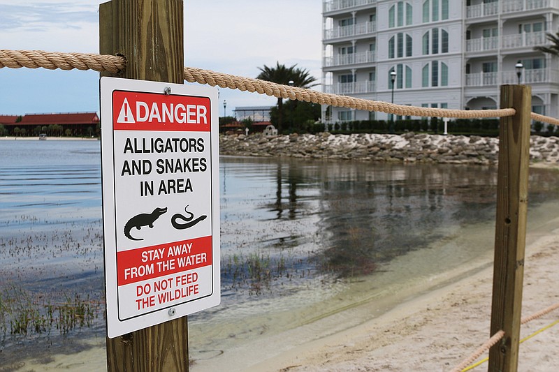 In this Friday, June, 17, 2016 photo released by Walt Disney World Resort, a new sign is seen posted on a beach outside a hotel at a Walt Disney World resort in Lake Buena Vista, Fla. Private family services have been scheduled  for a 2-year-old Nebraska boy killed by an alligator at Disney World. Authorities say an alligator pulled Lane Graves into the water last Tuesday, June 14, 2016, despite the frantic efforts of his father. Lane's body was recovered Wednesday.