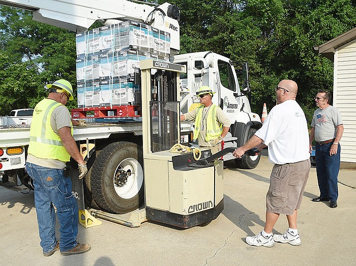 Roy Hall, left and Travis Britton, background left, assist Carlos Robinett as he uses a heavy-duty hand truck to lift the pallet of air conditioners from the flatbed truck at the Samaritan Center. In the background, at right, waiting to lend a hand is Samaritan Center volunteer Bill Surface.