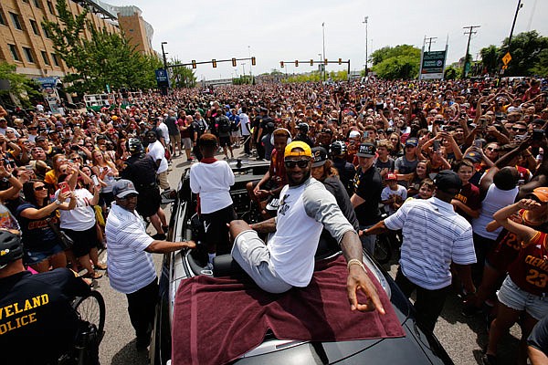 Cavaliers forward LeBron James and his family ride in the back of a car at the beginning of Wednesday's NBA championship parade in Cleveland.