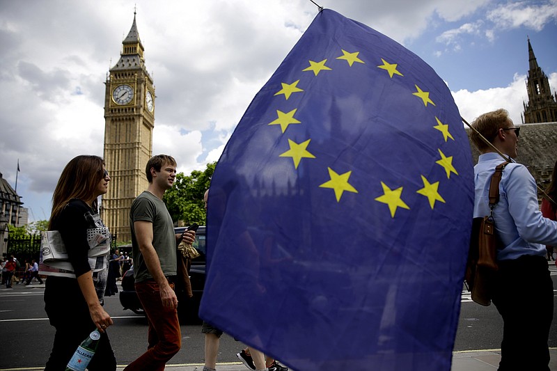 A remain supporter stops to talk to people Friday, June 24, 2016, as he walks around with his European flag across the street from the Houses of Parliament in London. Britain's Prime Minister David Cameron announced Friday that he will quit as Prime Minister following a defeat in the referendum which ended with a vote for Britain to leave the European Union.