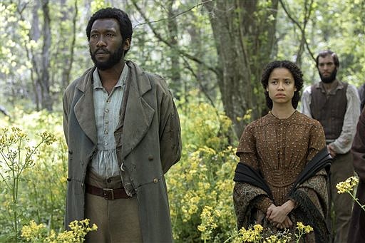 This image released by STX Productions shows Mahershala Ali, left, and Gugu Mbatha-Raw in a scene from "The Free State of Jones."
