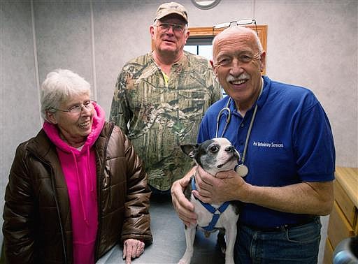 In this March 2015 photo provided by Pol Veterinary Services, veterinarian Jan Pol, right, poses with Mr. Pigglesworth and the dog's owners owners Loyd and Mable Frisbie at his clinic near Mount Pleasant, Mich. An appeals court on Friday, June 24, 2016, cleared Pol of misconduct when he saved the dog's life in 2011. Pol has a reality TV show on Nat Geo Wild called "The Incredible Dr. Pol."