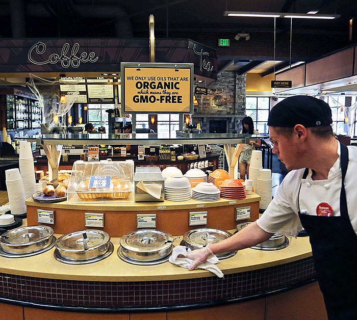 A grocery store employee wipes down a soup bar with a display informing customers of organic, GMO-free oils, in Boulder, Colorado.
