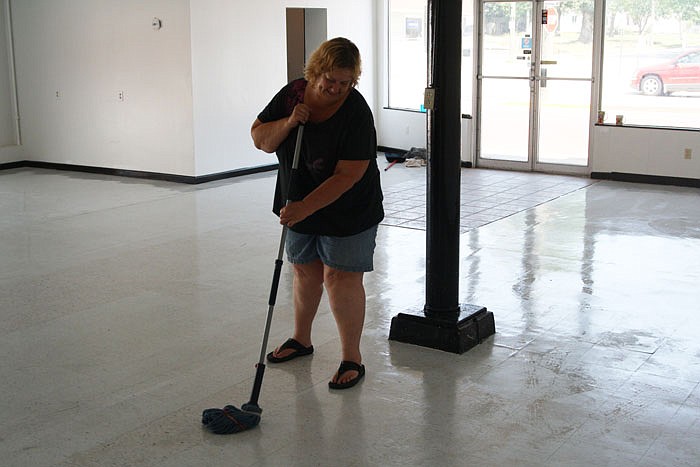 Faith Adams mops the floor at the new Treasure Island Thrift Store.