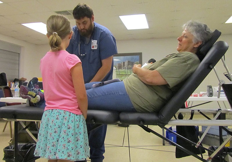 A girl and an American Red Cross worker comfort a blood donor at the Battle of the Badges Blood Drive on Friday, June 24, 2016, in Fulton.