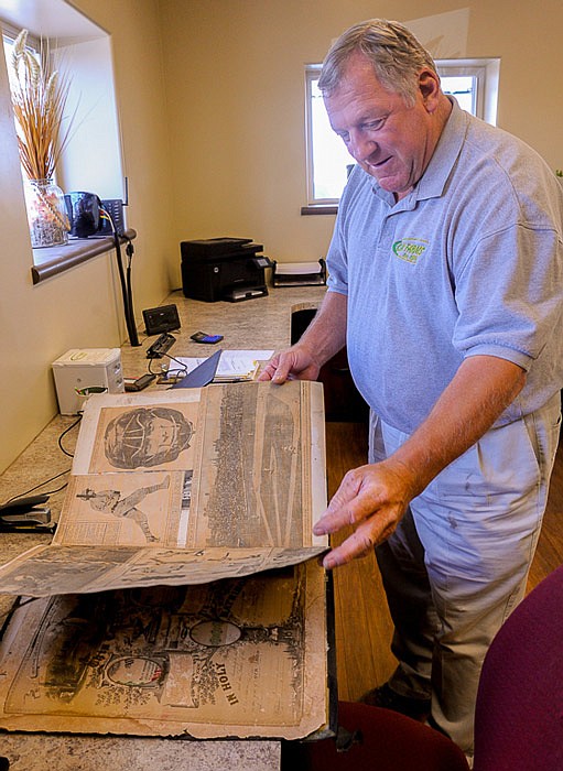 John Clay peruses an old, hard-covered store catalog, which boasts early newspaper clippings and photos of the St. Louis Cardinals collected by his grandparents and great uncles.