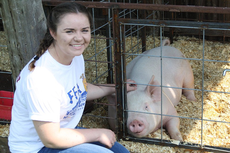 Alyssa Reid poses next to one of her show pigs at her family's farm near New Bloomfield, Mo.
