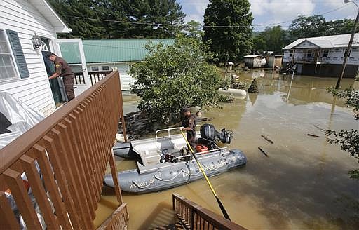 West Virginia Natural Resources police officer Chris Lester, left, walks into the top floor of a flooded home as he and Lt. Dennis Feazell search homes in Rainelle, W. Va., Saturday, June 25, 2016. About 32,000 West Virginia homes and businesses remain without power Saturday after severe flooding hit the state. The West Virginia Division of Homeland Security and Emergency Management also said Saturday that more than 60 secondary roads in the state were closed. 