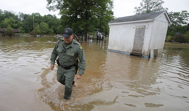 West Virginia State Trooper C.S. Hartman, walks from a shed that he checked out as he and other crews search homes in Rainelle, W. Va., Saturday, June 25, 2016. Heavy rains that pummeled West Virginia left multiple people dead, and authorities said Saturday that an unknown number of people in the hardest-hit county remained unaccounted for.
