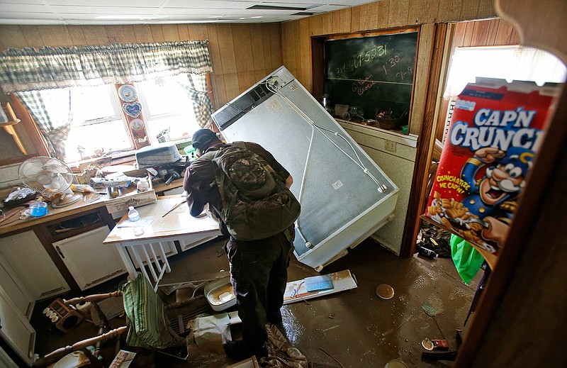 West Virginia Natural Resources police officer Chris Lester searches a flooded home in Rainelle, W. Va., Saturday, June 25, 2016. Heavy rains that pummeled West Virginia left multiple people dead, and authorities said Saturday that an unknown number of people in the hardest-hit county remained unaccounted for. 