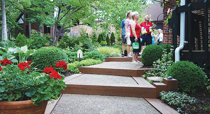 Cheryl and Don Carter, in red, and Alan and Jeanne Nelson, in back, tour the home garden of Nancy Duggins Vostal at 733 Hobbs Road on Sunday. The garden was one of six gardens on the annual Bittersweet Garden Tour.