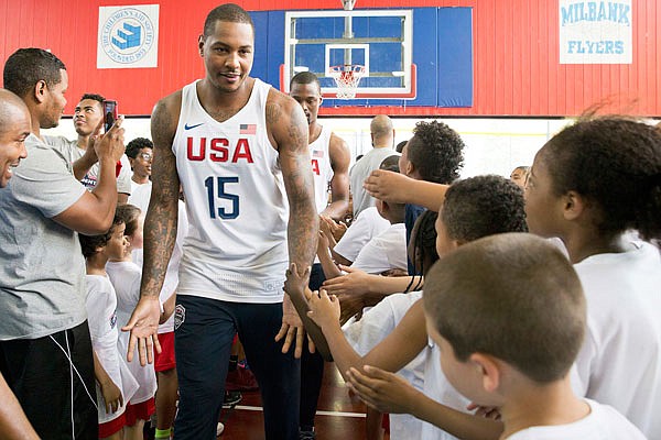 U.S. men's Olympic basketball team player Carmelo Anthony (left) greets children that participated in a basketball clinic as he arrives for a news conference Monday in New York.