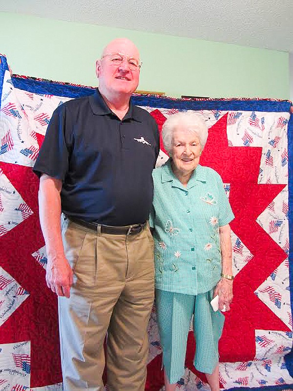 Ray and Jean Allee stand in front of the Quilt of Valor.