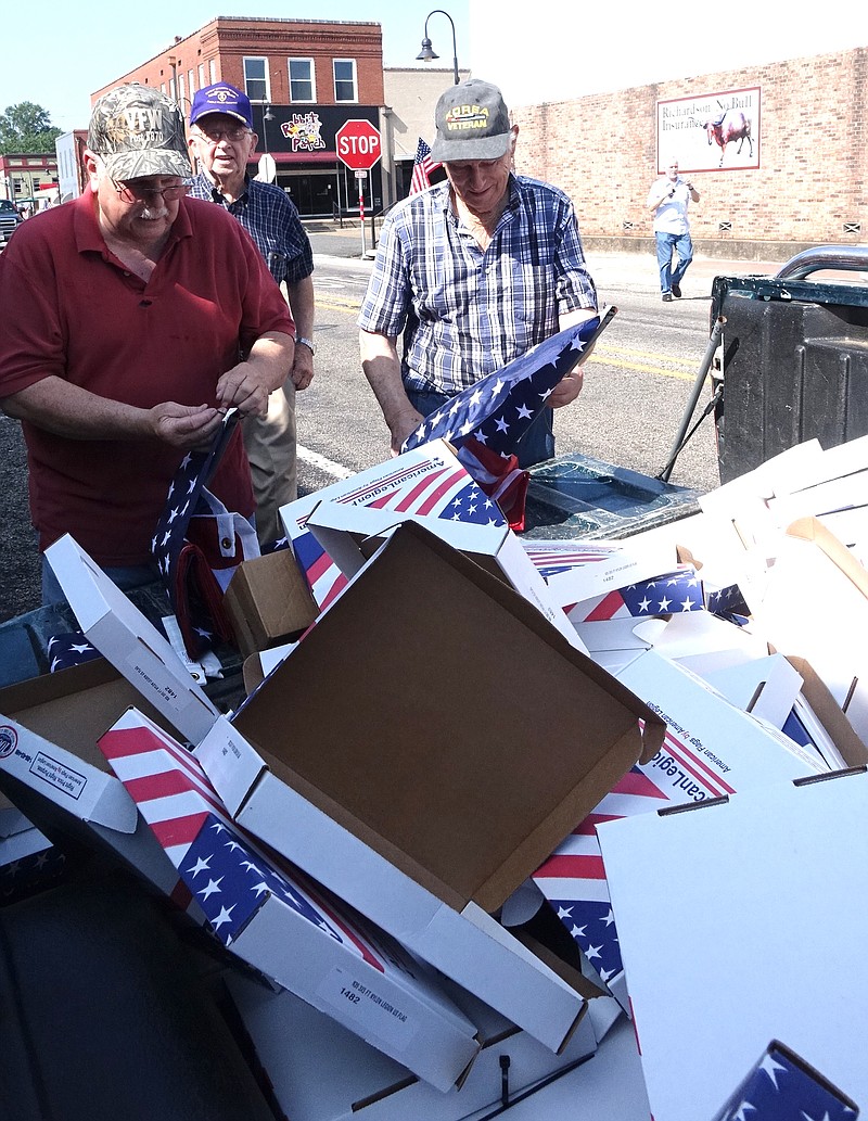 Mike Lee, left, Roger Matlock and Bob Steger of J.E. Manning American Legion Post 258 open the more-than-100 new flags to be flown in Atlanta.