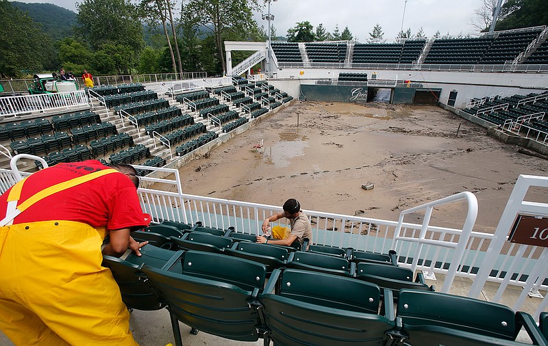 A workers clean seats in the stands at Center Court at Creekside tennis court at the Greenbrier Resort in White Sulphur Springs, W. Va., Tuesday, June 28, 2016. Flooding from heavy rains last week damaged the course canceling the PGA Tour event scheduled for next week and closing the Hotel.