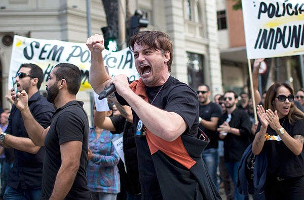 A police officer yells into a microphone during a protest demanding better labor conditions in Rio de Janeiro, Brazil on Monday. Just weeks ahead of the Olympic Games, Rio de Janeiro's security forces are so pressed for funds that some have to beg for donations of pens, cleaning supplies and even toilet paper, fueling worries about safety at the world's premier sporting event.
