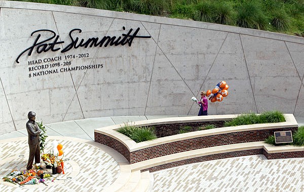 A fan brings flowers and balloons to lay at the Pat Summitt Plaza on Tuesday at the University of Tennessee campus in Knoxville, Tenn. Summitt, the winningest coach in Division I college basketball history, died Tuesday morning. She was 64.