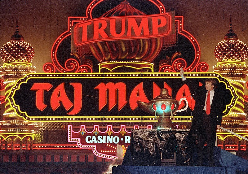 In this April 5, 1990 file photo, Donald Trump stands next to a genie's lamp as the lights of his Trump Taj Mahal Casino Resort light up during ceremonies to mark its opening in Atlantic City, N.J. Soon after the opening, Trump owed $70 million to 253 contractors employing thousands who built the domes and minarets, put up the glass and drywall, laid the pipes and installed everything from chandeliers to bathroom fixtures. The next year, when the casino collapsed into bankruptcy, those owed the most got only 33 cents in cash for each dollar owed, with promises of another 50 cents later. It took years to get the rest, assuming the companies survived long enough to collect. 