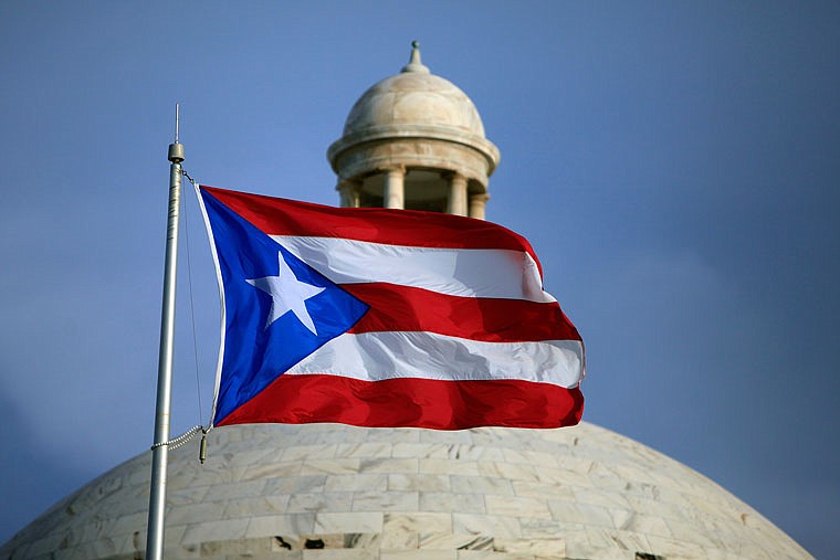 The Puerto Rican flag flies in front of Puerto Rico's Capitol last year in San Juan. Congress edged closer to delivering relief to debt-stricken Puerto Rico as the Senate on Wednesday cleared the way for passage of a last-minute financial rescue package for the territory of 3.5 million Americans.