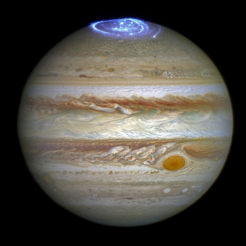 This composite image provided by NASA on Thursday, June 30, 2016 illustrates auroras on the planet Jupiter. This view was produced by NASA using a photograph made by the Hubble Space Telescope in spring 2014, and ultraviolet observations of the auroras in 2016. Earth's polar lights are triggered by solar storms, which occur when a cloud of gas from the sun encounters the planet's magnetic field. Jupiter's powerful auroras are sparked by the planet's own rotation. 