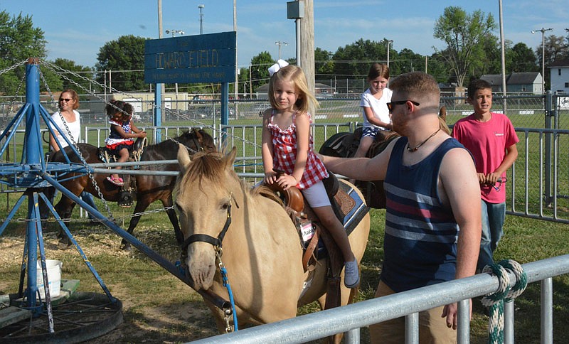 Brice Cassile, right, leads his youger sister, Bentley Bosch on the pony ride at the Holts Summit festival Friday, July 1, 2016. The family-owned business, Great Events LLC, has about 30 ponies on their 110-acre farm, and they travel around Missouri for festivals and fairs.
