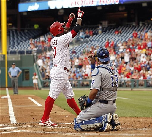 Philadelphia Phillies' Odubel Herrera, left, points skyward as he walks past Kansas City Royals catcher Salvador Perez after hitting a solo home run during the first inning of a baseball game Friday, July 1, 2016, in Philadelphia. 