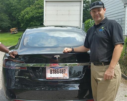 In this 2015 photo provided by his neighbor, Krista Kitchen, Joshua Brown stands by his new Tesla electric car near his home in Canton, Ohio. Brown died in an accident in Florida on May 7, 2016 in the first fatality from a car using self-driving technology. According to statements by the government and the automaker, his vehicle's cameras didn't make a distinction between the white side of a turning tractor-trailer and the brightly lit sky while failing to automatically activate its brakes. 