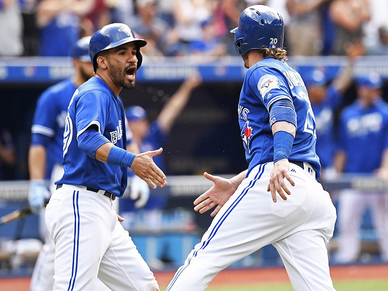 Toronto Blue Jays' Josh Donaldson, right, and Devon Travis celebrate after they scored on a double by Michael Saunders against the Cleveland Indians during eighth-inning baseball game action, in Toronto, Saturday, July 2, 2016. 