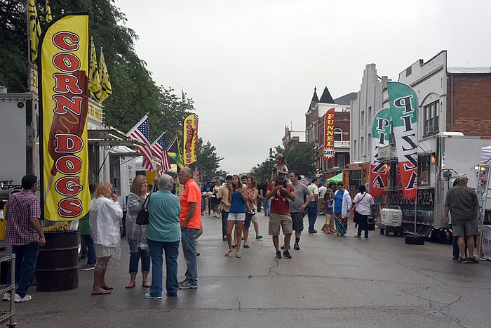 People mill around the soggy  Food Court on High Street during the Salute to America on Sunday.