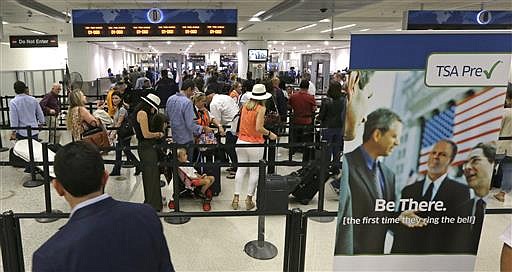 In this Thursday, May 26, 2016, photo, travelers stand in line as they prepare to pass through a Transportation Security Administration checkpoint at Miami International Airport, in Miami.