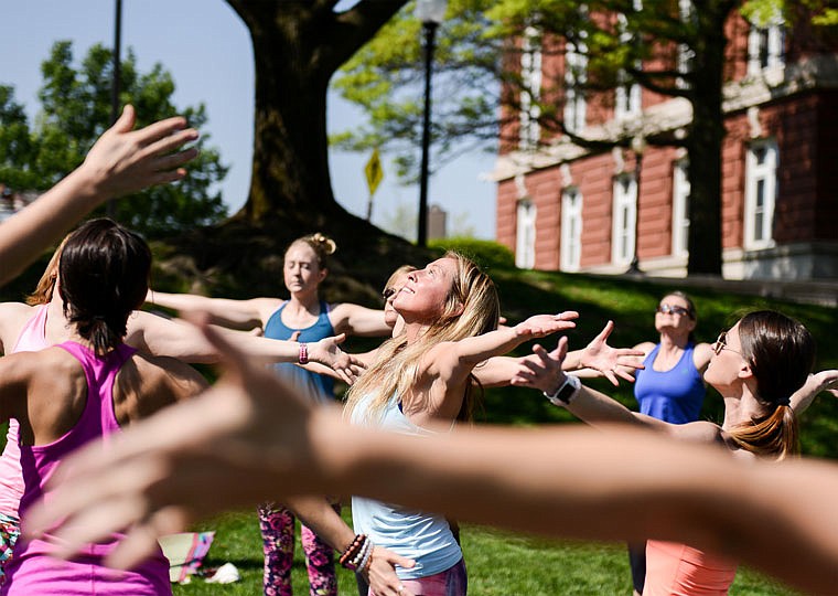 Megan Sappington, owner of Wilson's Yoga Studio, center, leads a group with outstretched arms during a sun salutation in April in honor of Earth Day on the Capitol lawn. 