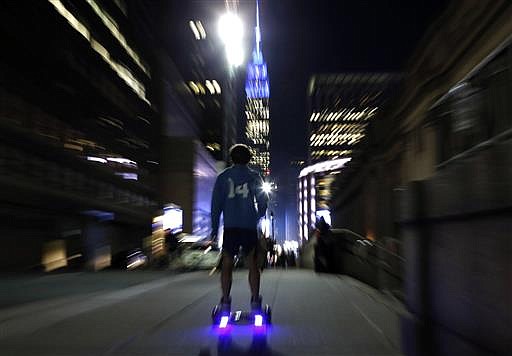 In this Oct. 21, 2015, file photo, a young man rides a hoverboard along a Manhattan street toward the Empire State Building in New York.