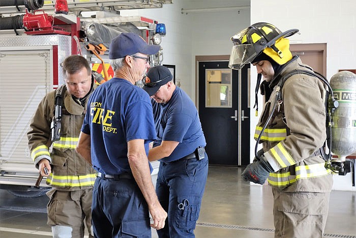 Fire Chief Todd Farley, left, and firefighters Gene Nelson and Jeremy Milam help a prospective volunteer with his equipment.