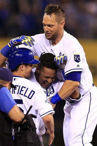 Kansas City Royals' Whit Merrifield, left, Alex Gordon, top right, congratulate teammate Salvador Perez, middle, after his game-winning 2-RBI double during the ninth inning of a baseball game against the Seattle Mariners at Kauffman Stadium in Kansas City, Mo., Thursday, July 7, 2016. The Royals defeated the Mariners 4-3.