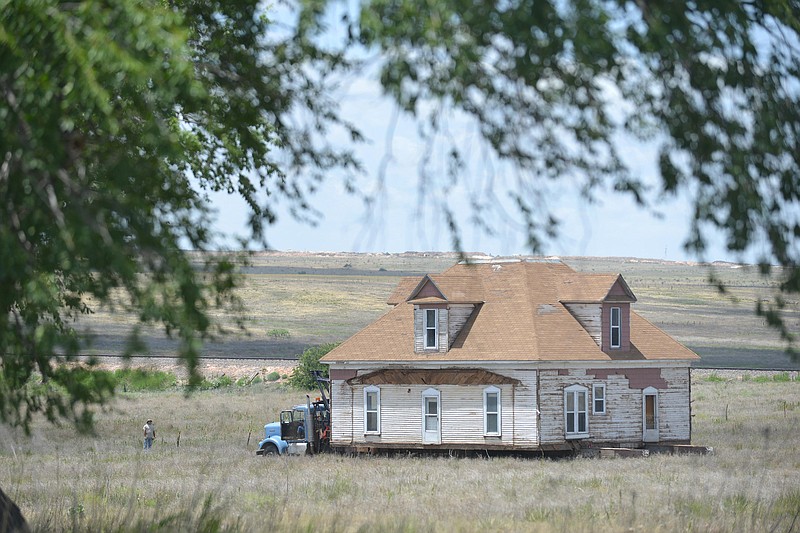 In a Monday, June 27, 2016 photo, house owner Paul Burks and crews with McDowell House and Structure Moving haul a historic 1900s home across an 80-acre pasture outside Canyon to its new location off Highway 60. The historic house was the home of W.F. Heller, a Civil War veteran and the first to farm in the area successfully in the late 1800s. 