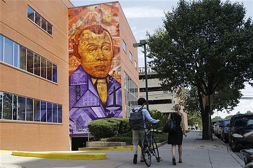 People walk past a Philadelphia Mural Arts Program piece depicting Bishop Richard Allen and the African Methodist Episcopal Church, in Philadelphia, Wednesday, July 6, 2016. The church marks its 200th anniversary in the city where it was founded by a former slave. 